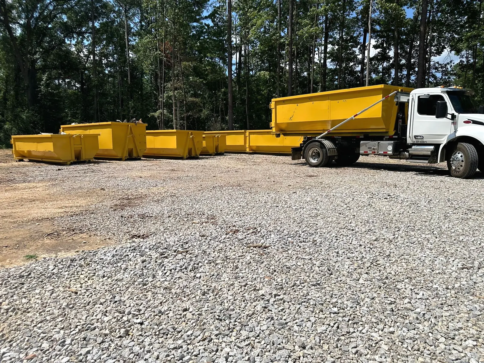 Dumpster Daddy truck with multiple yellow roll-off dumpster sizes